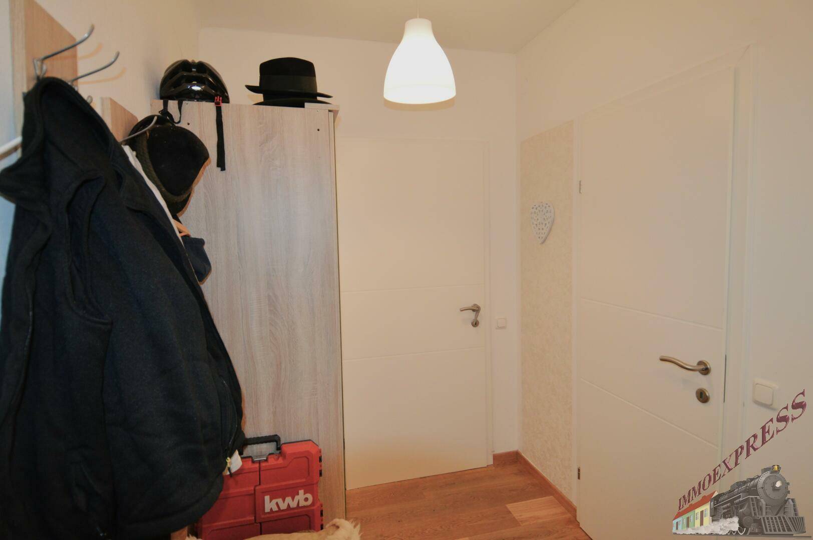 Heller Flur mit Garderobe und weißen Türen, die zu weiteren Räumen führen.