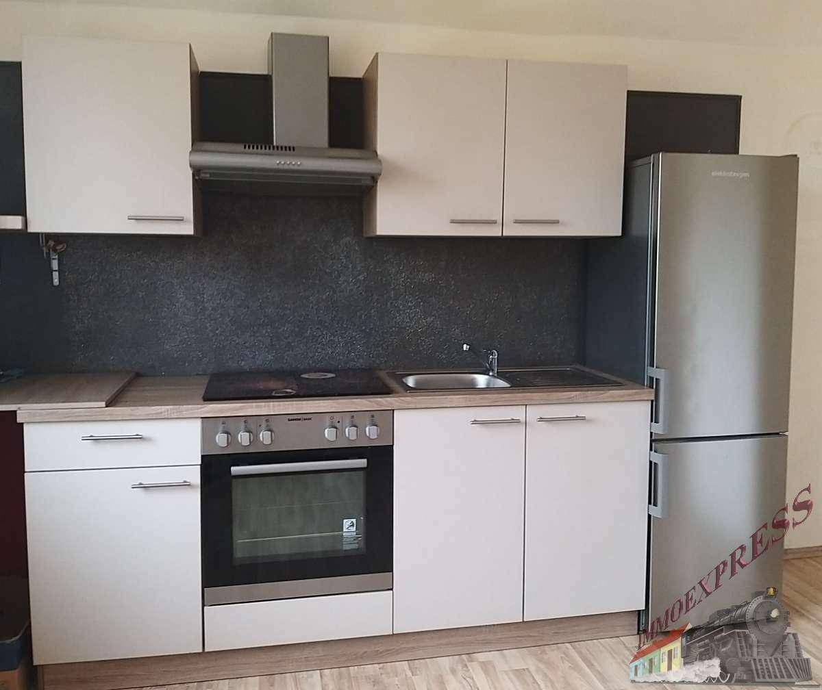 Kompakte Einbauküche mit hellen Schränken, integriertem Backofen und Kühlschrank.