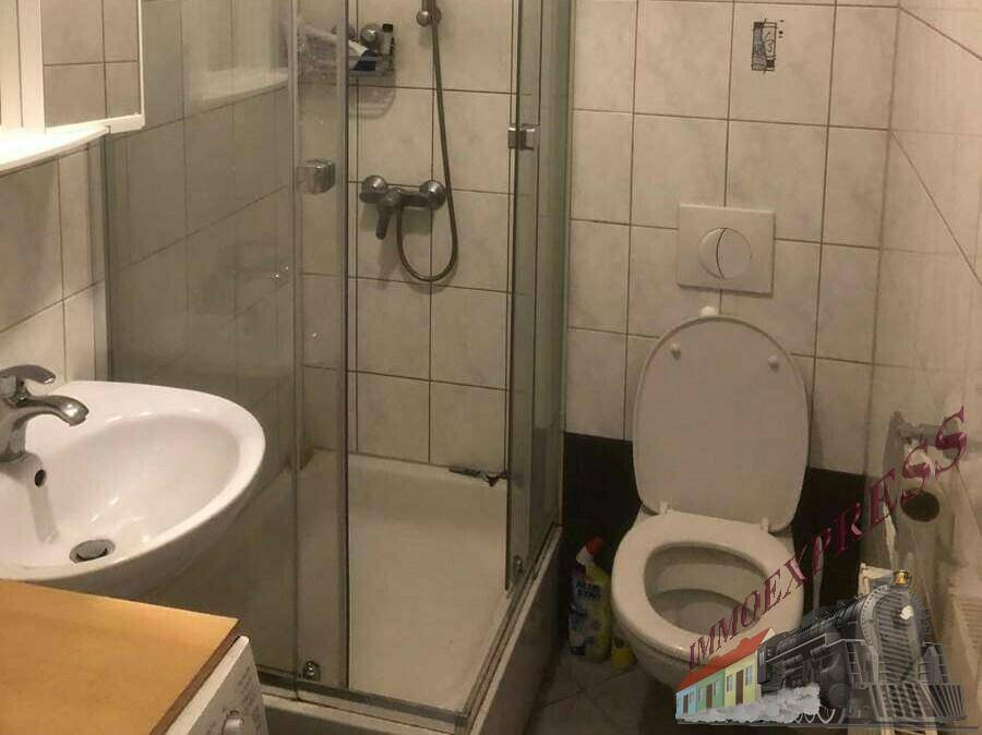 Kleines Badezimmer mit Duschkabine, WC und Waschbecken, gefliest in hellen Tönen.