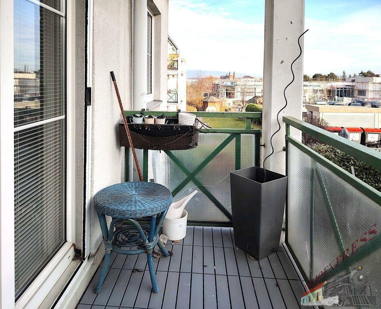 Kleiner Balkon mit Sitzgelegenheit und Blick auf die umliegenden Gebäude und die Stadt.