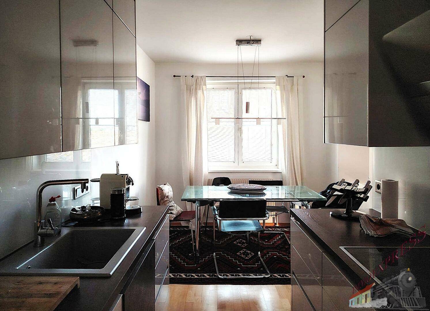 Moderne Küche mit Blick auf den Essbereich, ausgestattet mit glänzenden Schränken und Spüle.