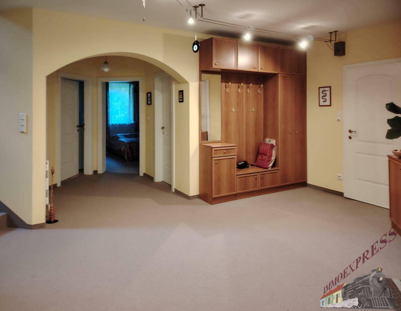 Heller Eingangsbereich mit integrierter Garderobe aus Holz und Zugang zu den angrenzenden Räumen.