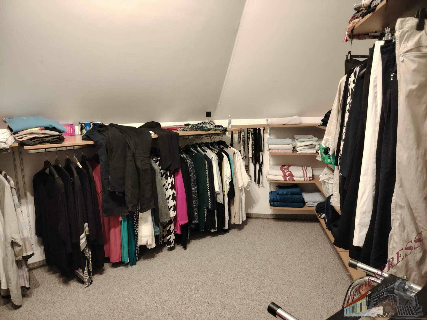 Praktischer begehbarer Kleiderschrank im Dachgeschoss mit Regalen und Kleiderstangen für viel Stauraum.