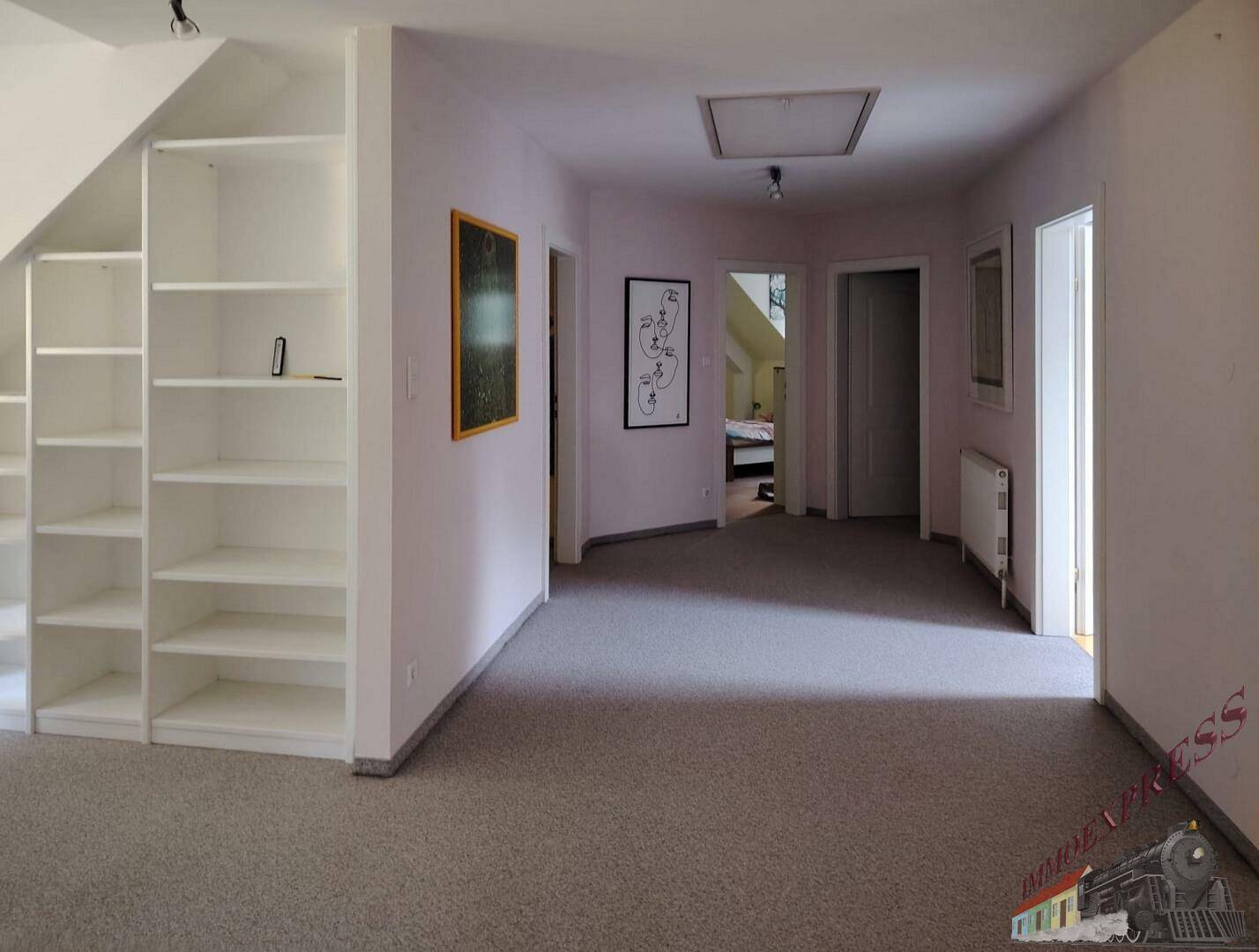 Geräumiger Flur im Obergeschoss mit Teppichboden, Einbauregalen und Zugang zu mehreren Zimmern.