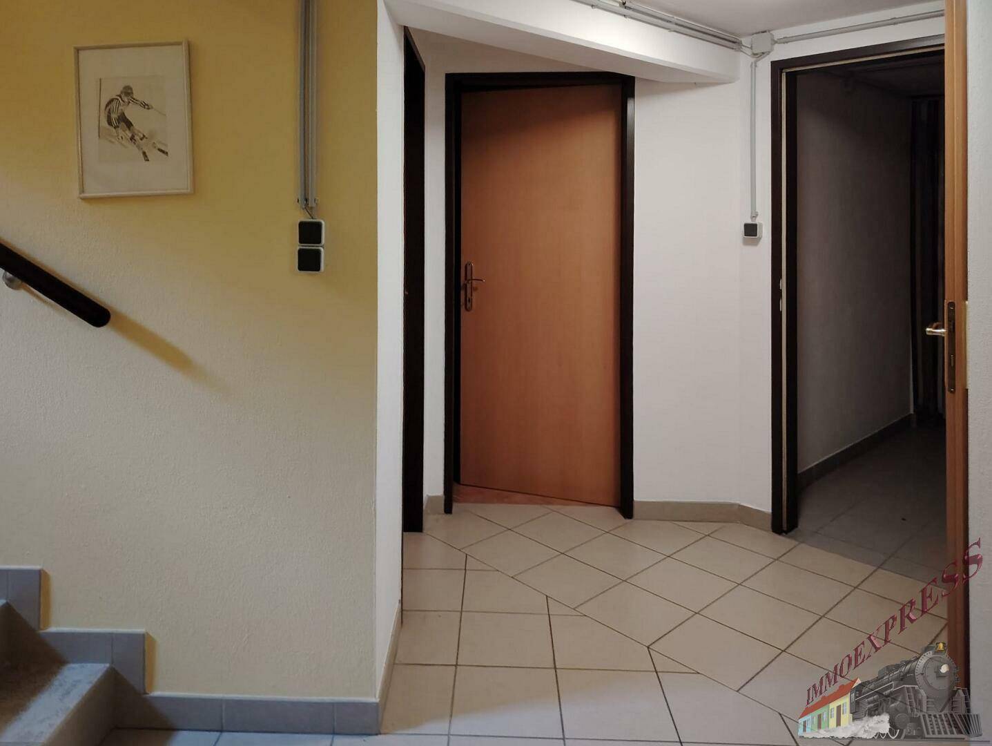 Heller Flur mit Fliesenboden und Zugang zu verschiedenen Räumen sowie einer Treppe.