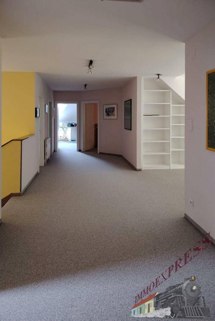 Langer Flur im Obergeschoss mit Teppichboden, Einbauregalen und Zugang zu den Zimmern.