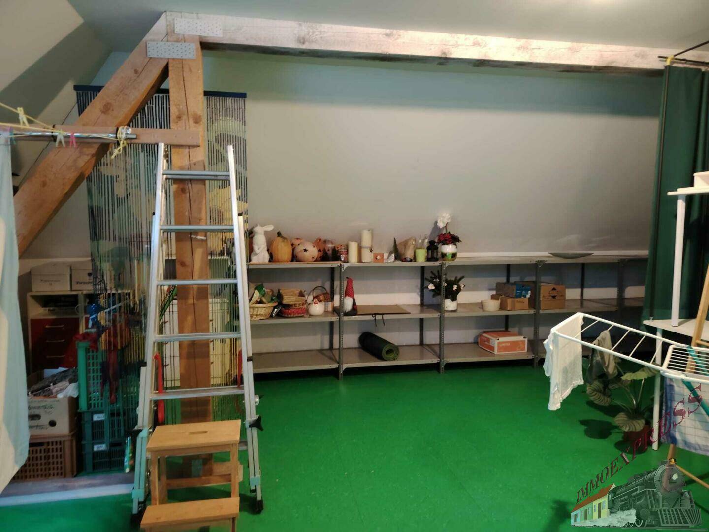 Geräumiger Dachboden mit grünem Boden, sichtbaren Holzbalken und vielseitigen Abstellmöglichkeiten.