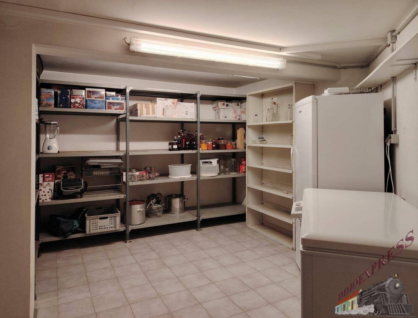 Geräumiger Abstellraum mit Regalen, Kühlschrank und Gefriertruhe für zusätzliche Lagerkapazität.