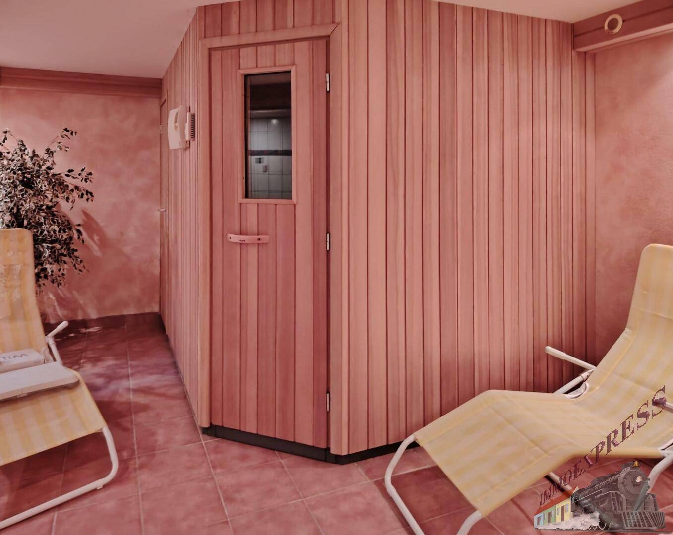 Entspannender Wellnessbereich mit einer Holzsauna und bequemen Liegestühlen für Erholung.