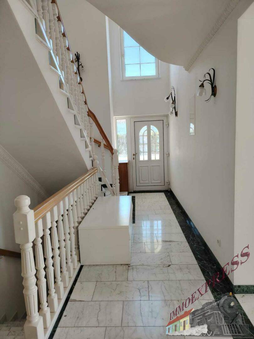 Heller Eingangsbereich mit Marmorboden und eleganter Treppe, die in die oberen Stockwerke führt.