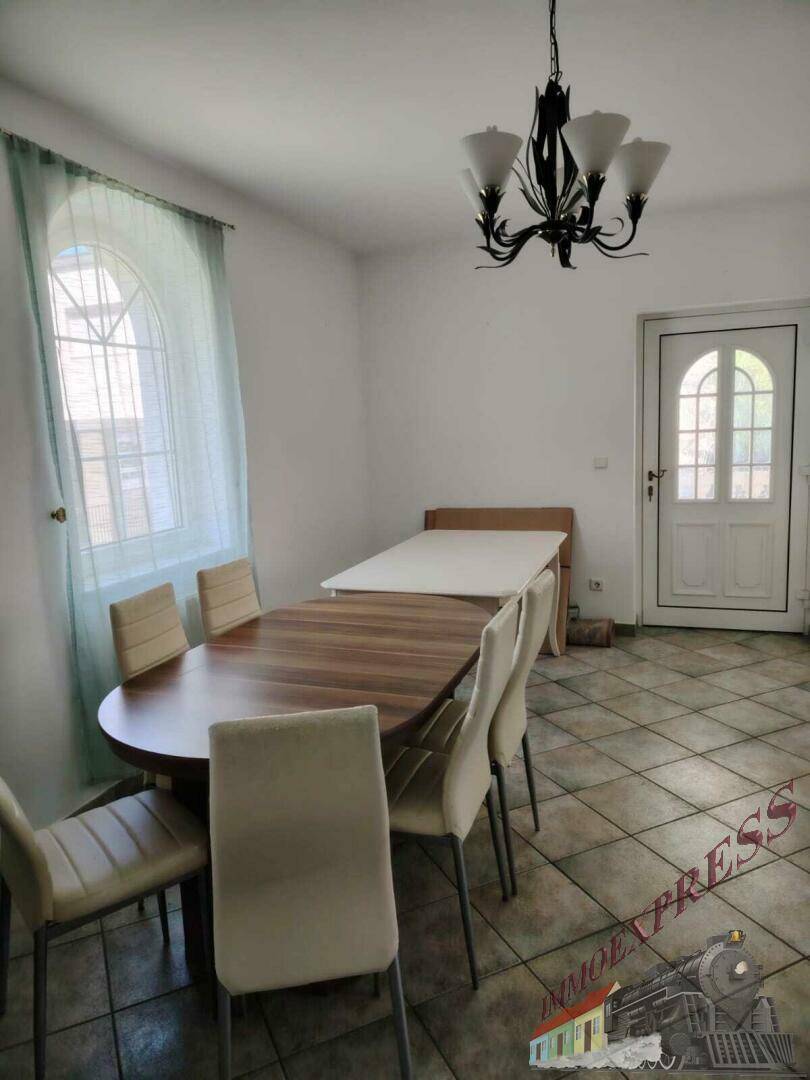 Essbereich mit Holztisch und Stühlen, hellen Fliesen und Zugang zur Außentür.