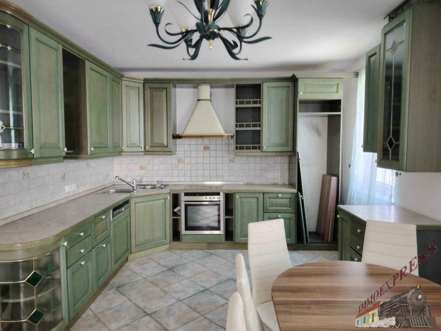 Geräumige Küche mit grünen Holzschränken, integriertem Backofen und Essbereich.