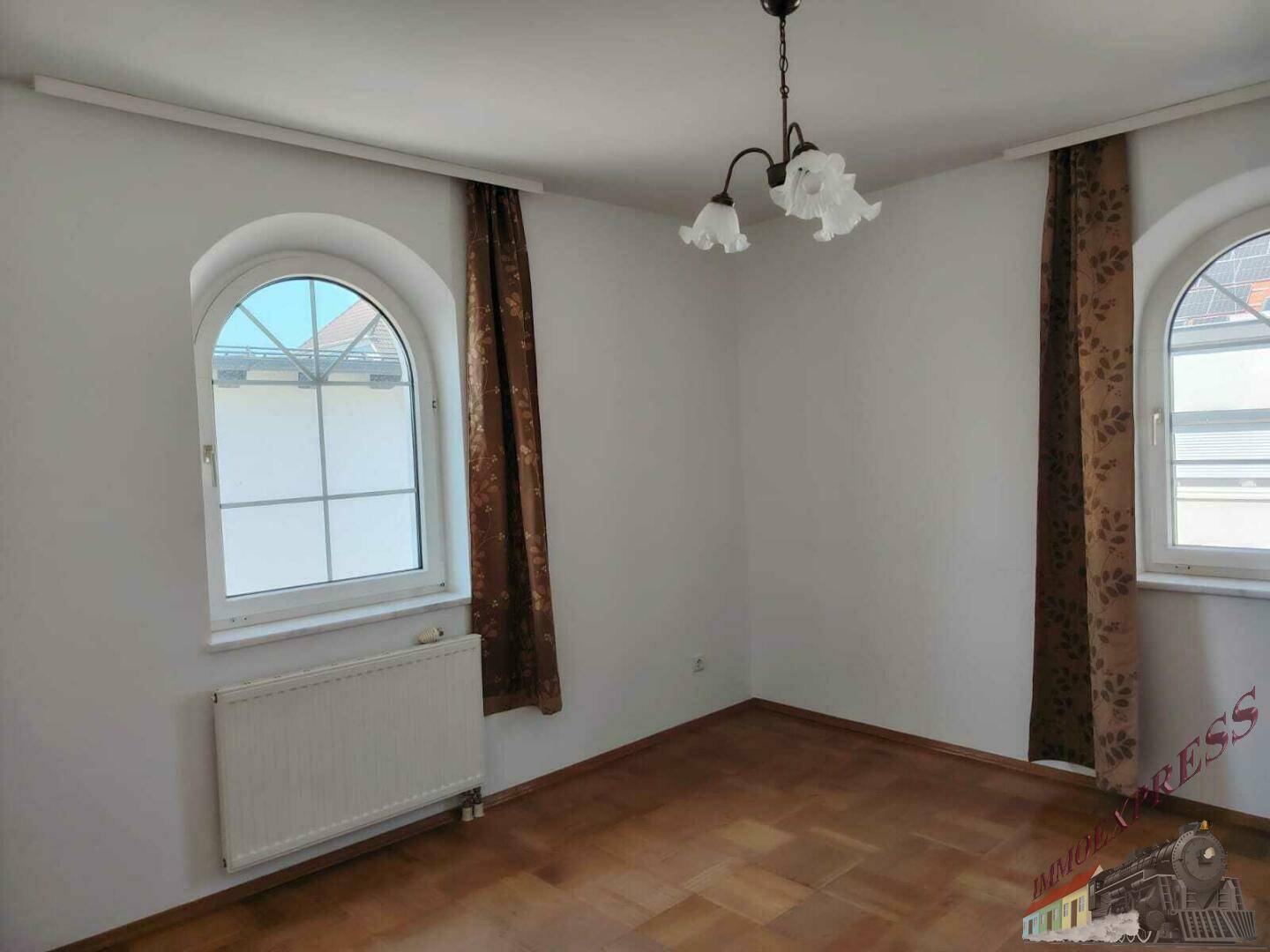 Lichtdurchflutetes Zimmer mit Parkettboden und großen Fenstern, bereit zur individuellen Gestaltung.