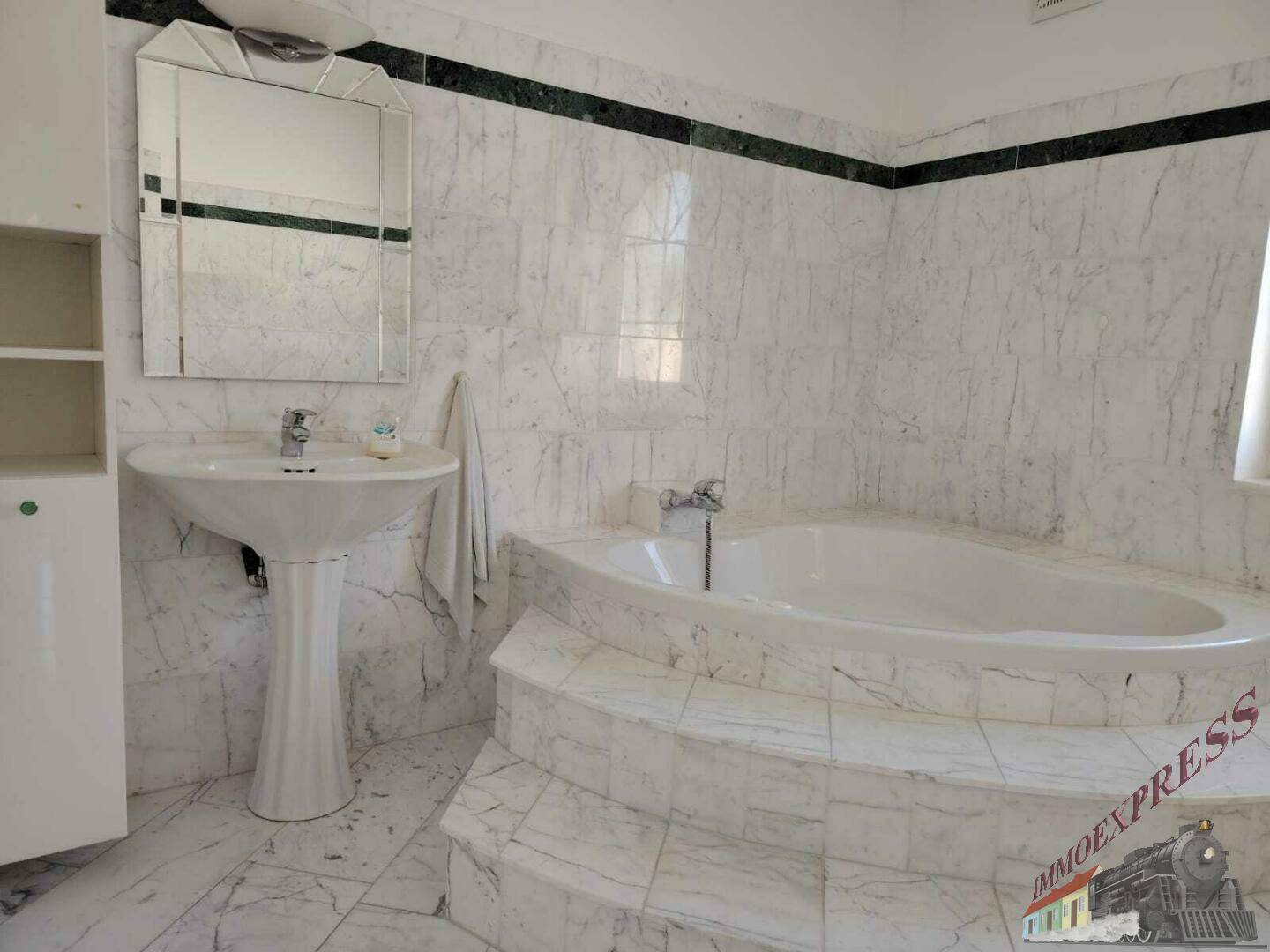 Großes Badezimmer mit Marmorfliesen, Eckbadewanne und Standwaschbecken, elegant gestaltet.