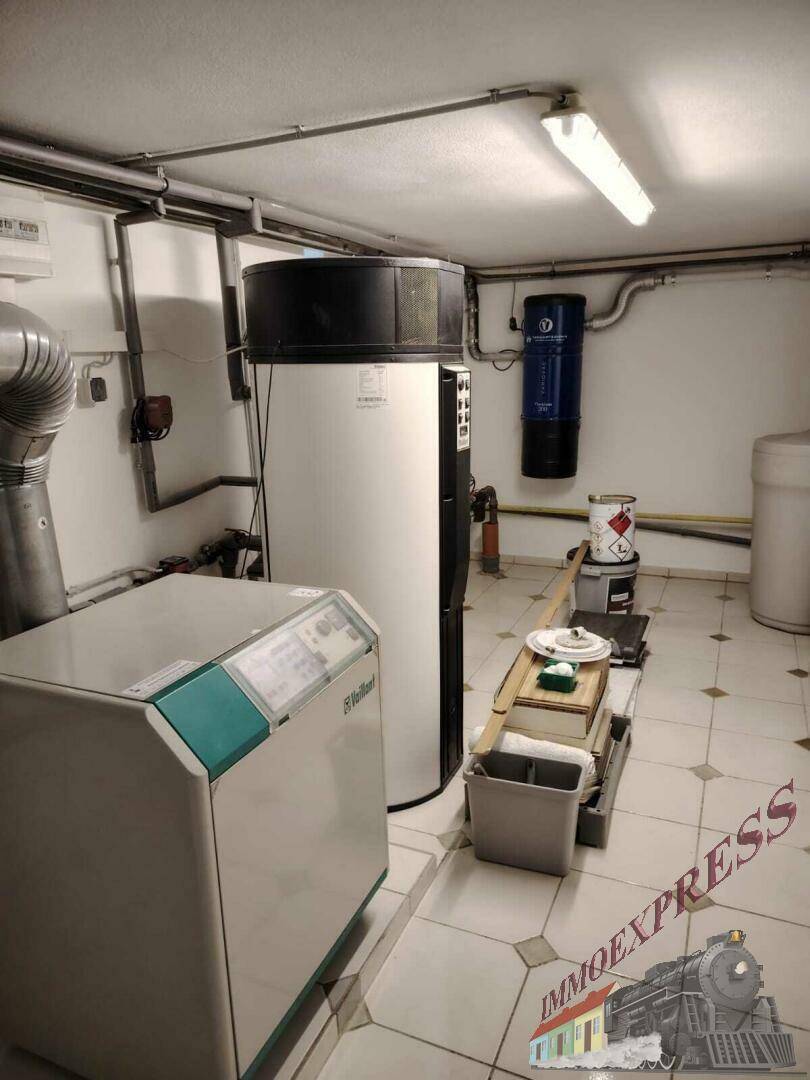 Technikraum im Keller mit Heizungsanlage und Warmwasserspeicher, funktional eingerichtet.