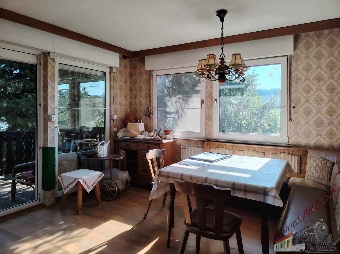 Gemütlicher Essbereich mit Holztisch, Stühlen und Zugang zu einem Balkon mit Aussicht.