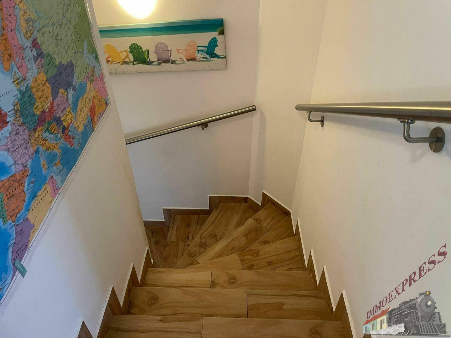 Treppenhaus mit Holzstufen und Handläufen, dekoriert mit einer Weltkarte.