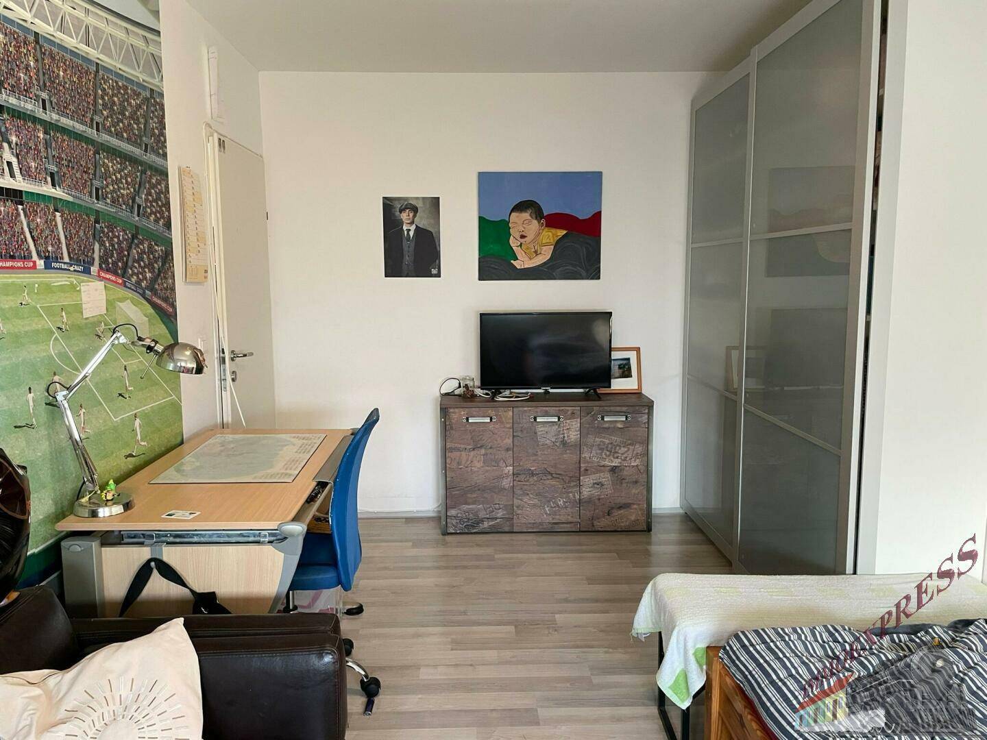 Jugendzimmer mit Schreibtisch, Bett und großem Schrank, hell und funktional eingerichtet.
