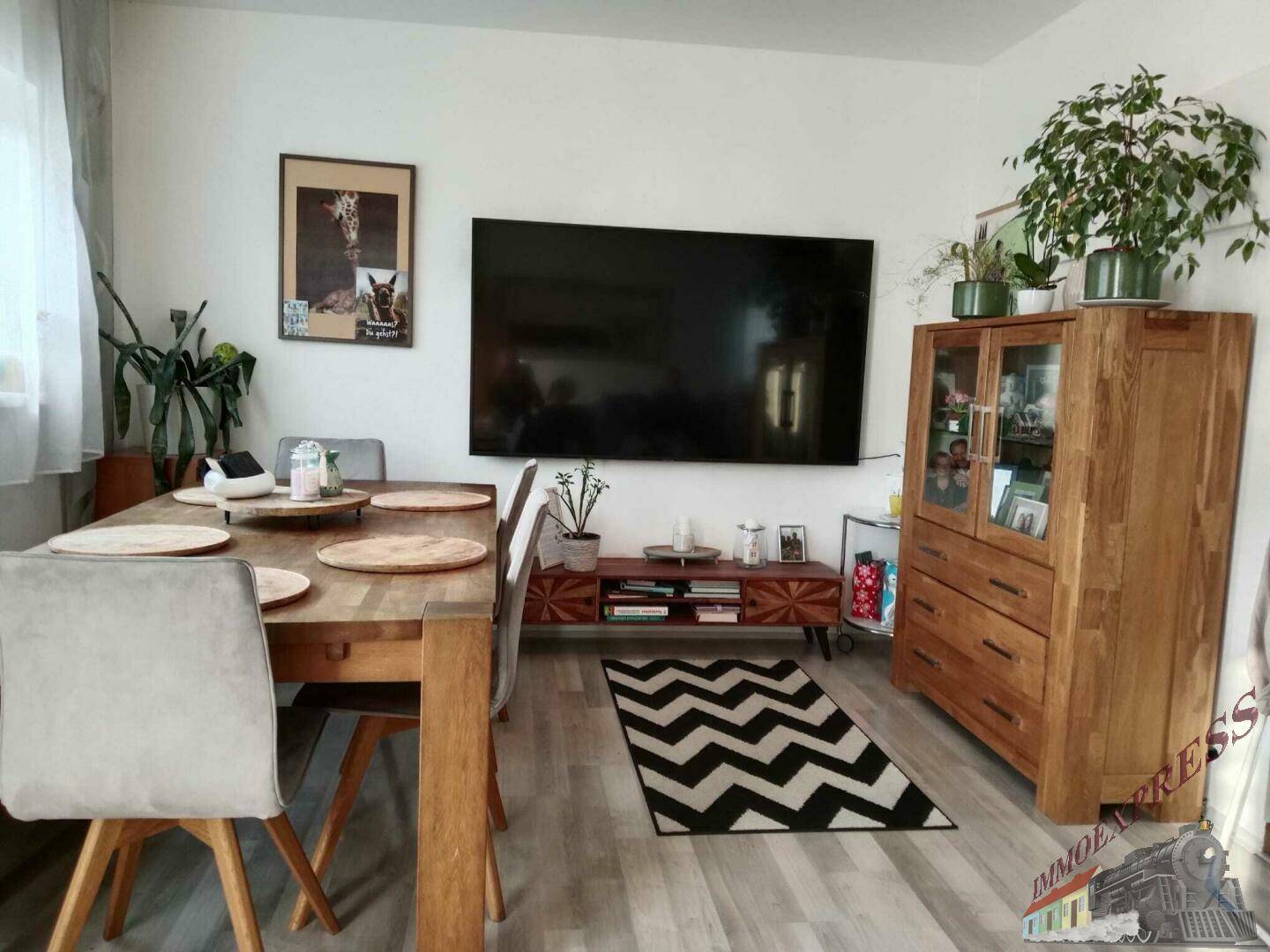 Heller Wohn- und Essbereich mit Holztisch, TV und modernem Sideboard.