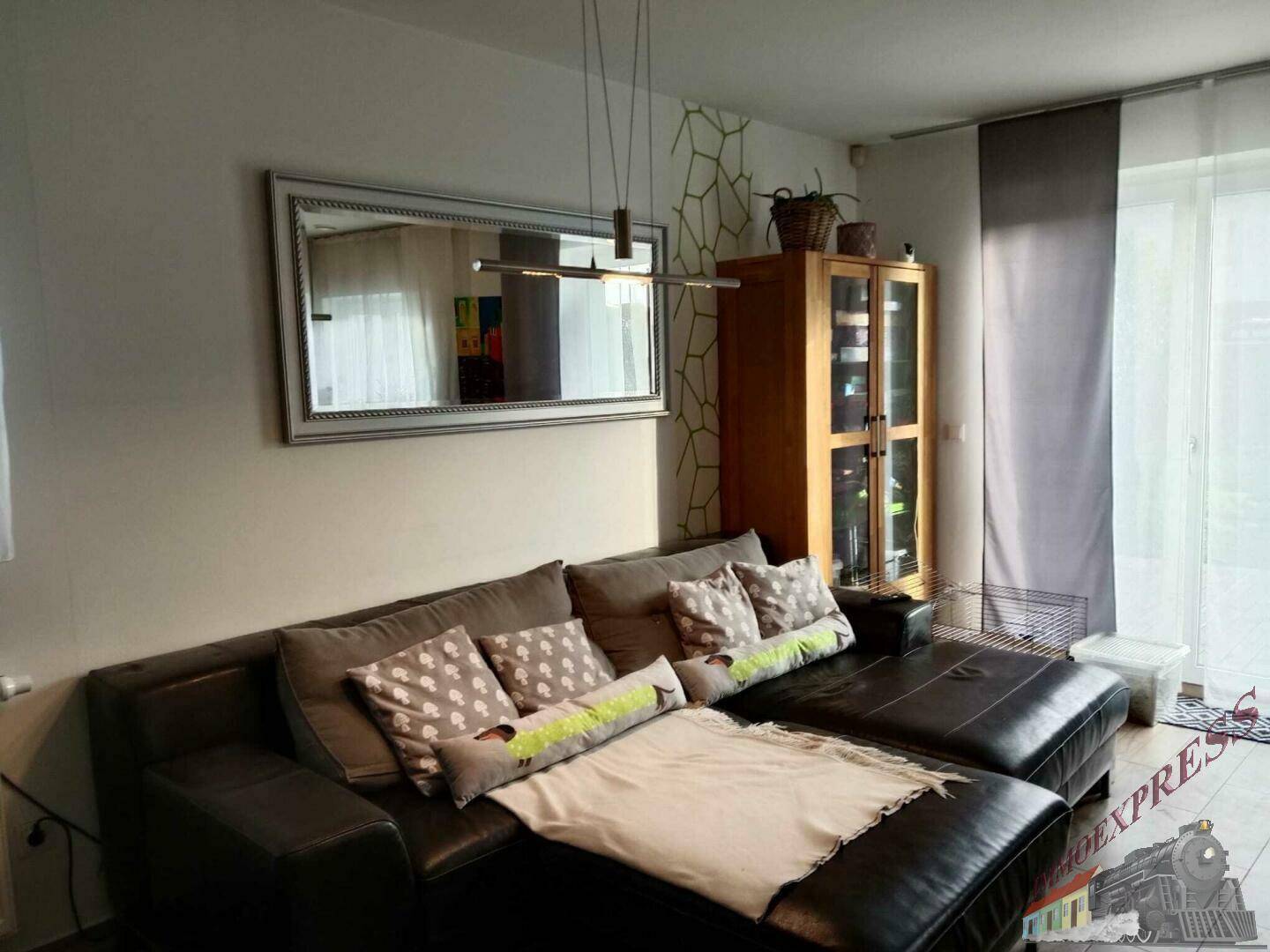 Gemütliches Wohnzimmer mit großem Ecksofa, Spiegel und modernem Hängeregal.