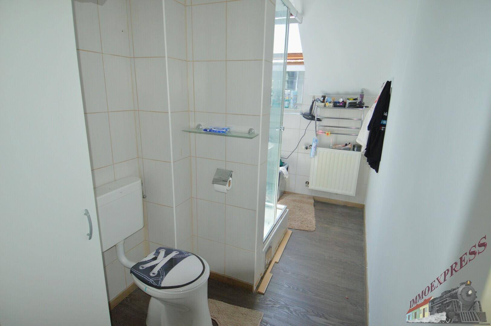 Modernes Badezimmer im Dachgeschoss mit Dusche und Toilette.