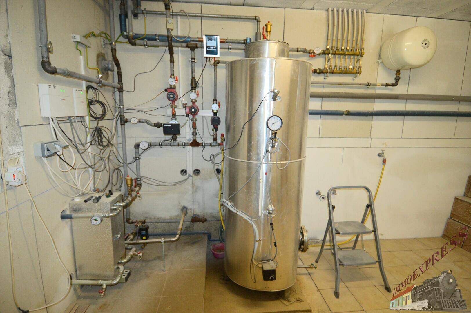 Detaillierte Ansicht der Heizungsanlage mit großem Tank und komplexen Rohrleitungen im Technikraum.