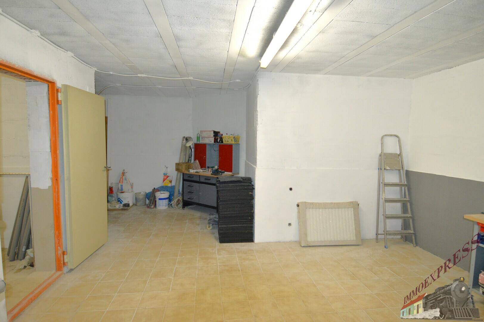 Geräumiger Kellerraum mit Fliesenboden, einer Werkbank und einer Leiter, ideal für handwerkliche Tätigkeiten.