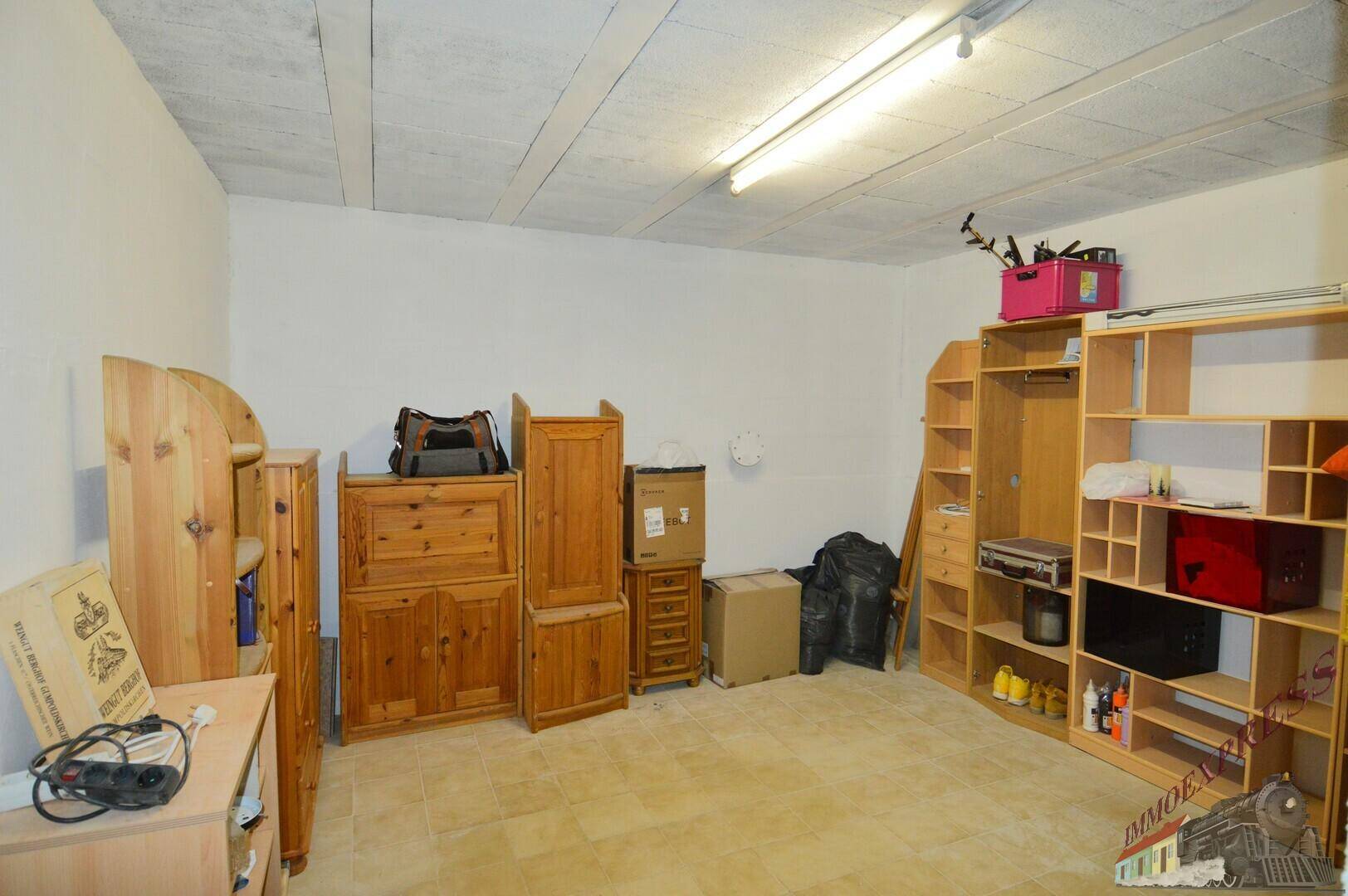 Kellerraum mit Fliesenboden, ausgestattet mit Holzschränken und Regalen für vielfältige Lagerzwecke.