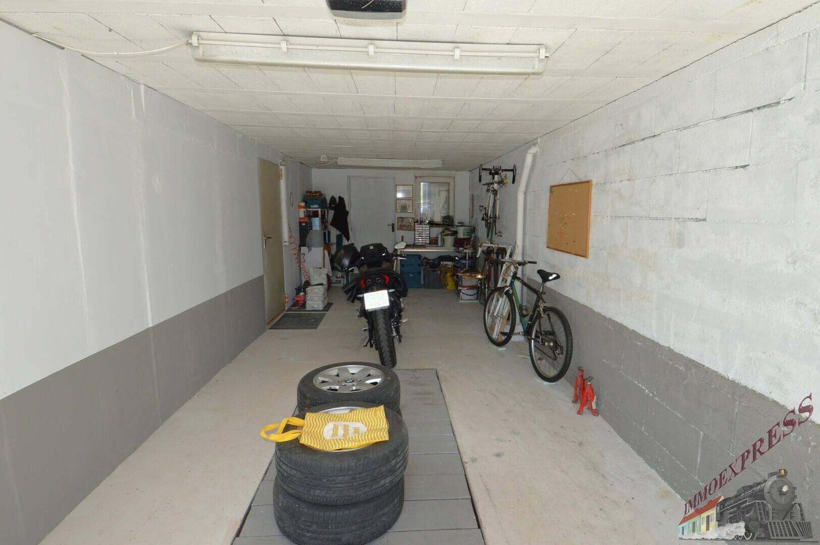 Geräumige Garage mit Betonwänden, Platz für Motorräder und Fahrräder sowie Reifenlagerung.