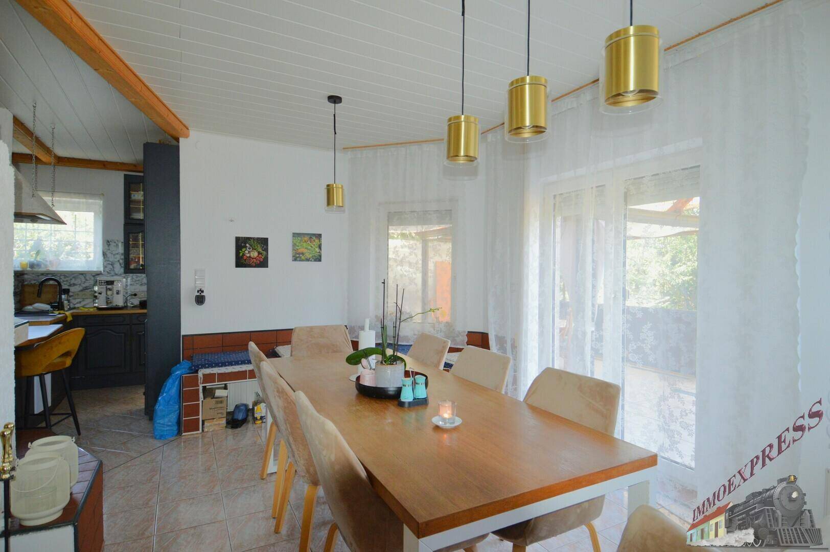 Essbereich mit großem Holztisch, bequemen Stühlen und Zugang zur Terrasse.