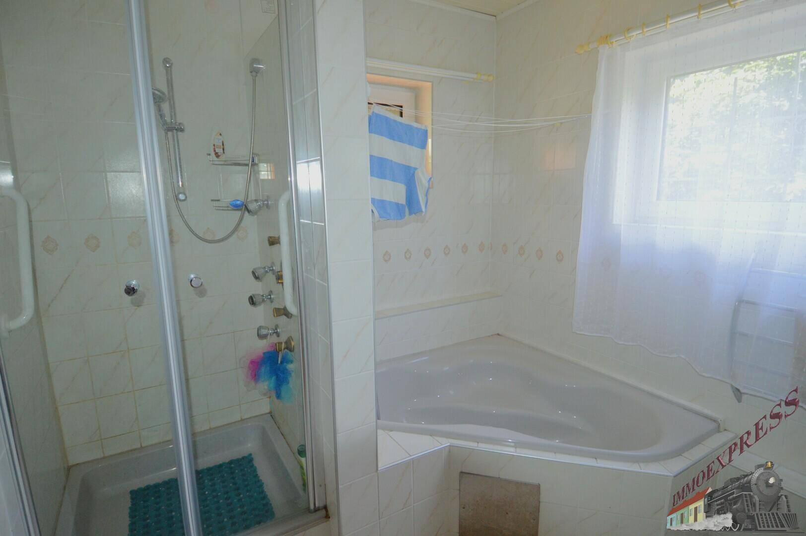 Badezimmer mit Eckbadewanne, Duschkabine und hellen Fliesen.
