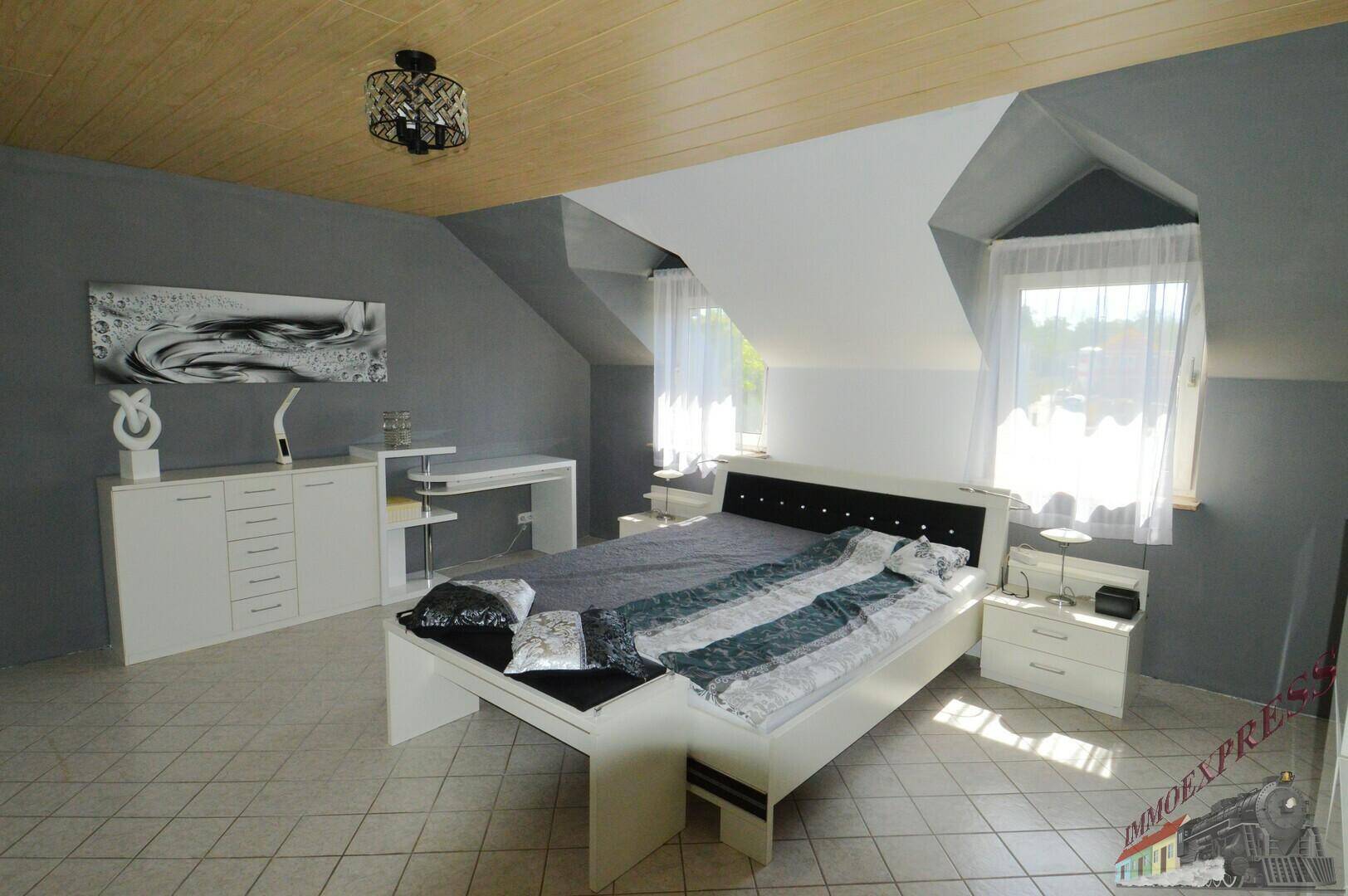 Modernes Schlafzimmer im Dachgeschoss mit Doppelbett, Schreibtisch und Dachschrägen.
