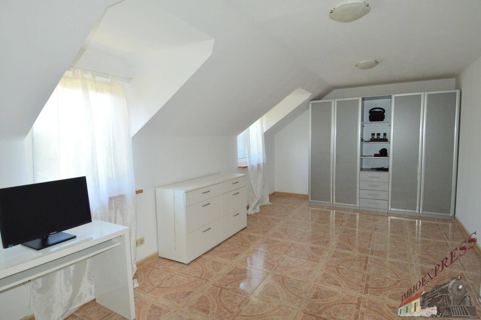 Dachgeschosszimmer mit Schrank, Kommode und Schreibtisch.