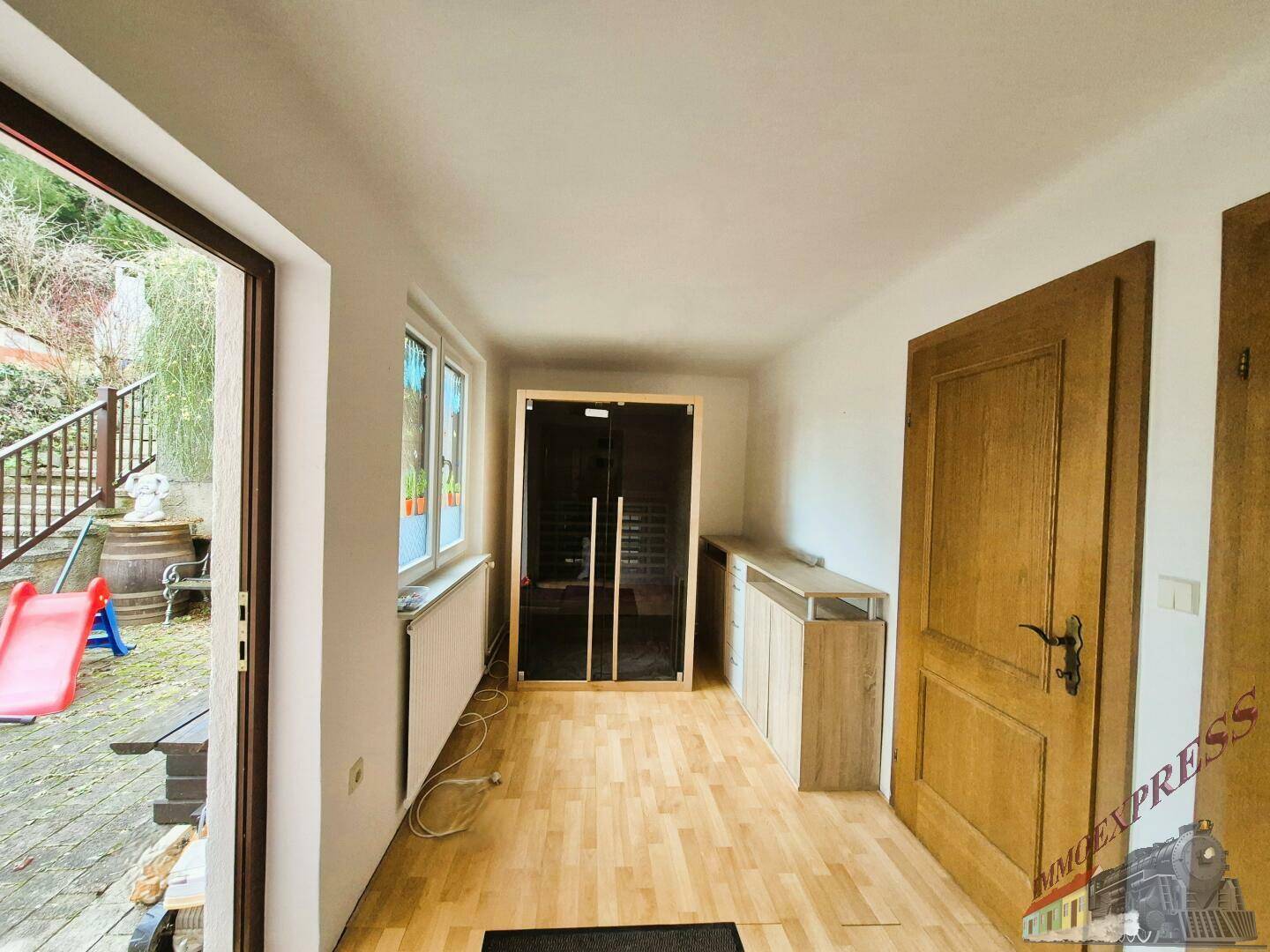 Flur mit Holzboden, einer Infrarotkabine und Zugang zum Außenbereich.
