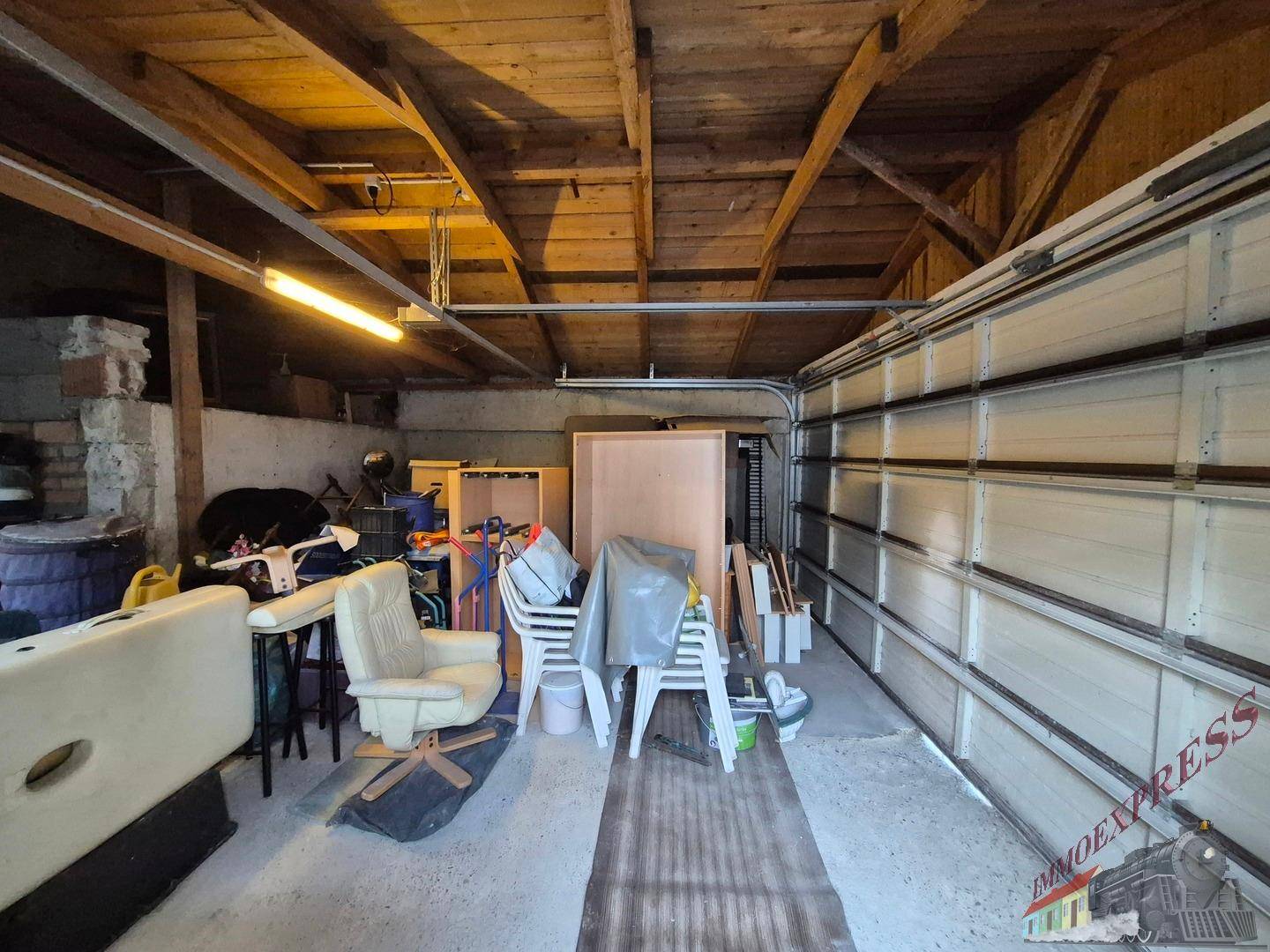 Garage mit sichtbaren Holzbalken, Lagerfläche und Garagentor.