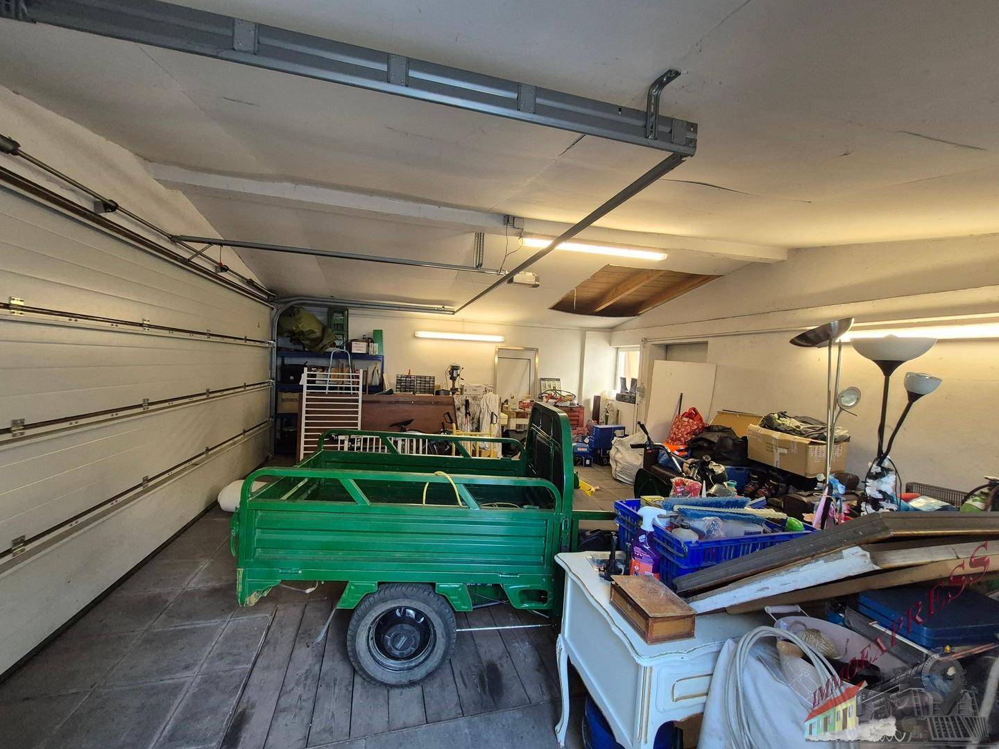 Geräumige Garage mit einem kleinen Fahrzeug und verschiedenen Lagergegenständen.