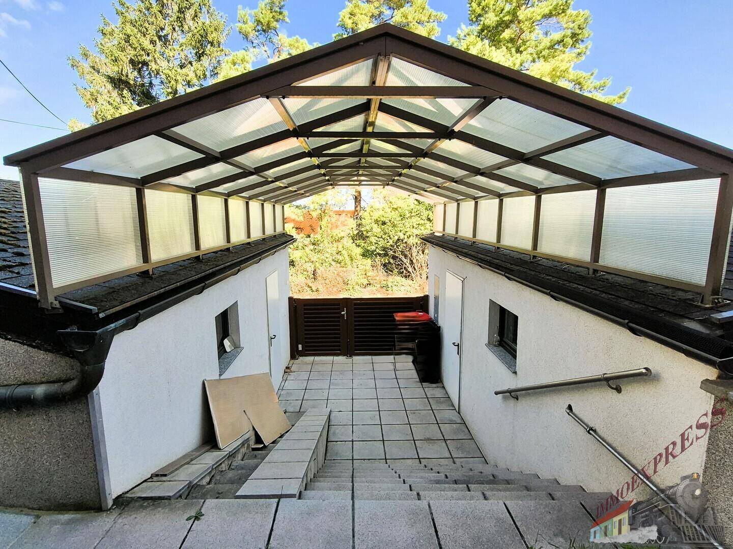 Überdachter Eingangsbereich mit Treppen, Rampe und Handlauf.