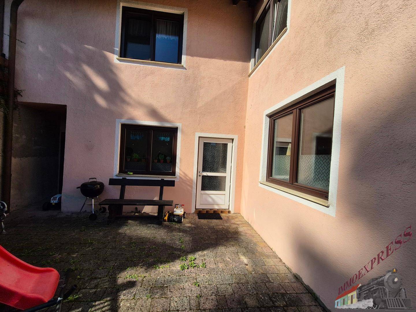 Gepflasterter Innenhof an der Rückseite des Hauses mit einem Kinderspielgerät.