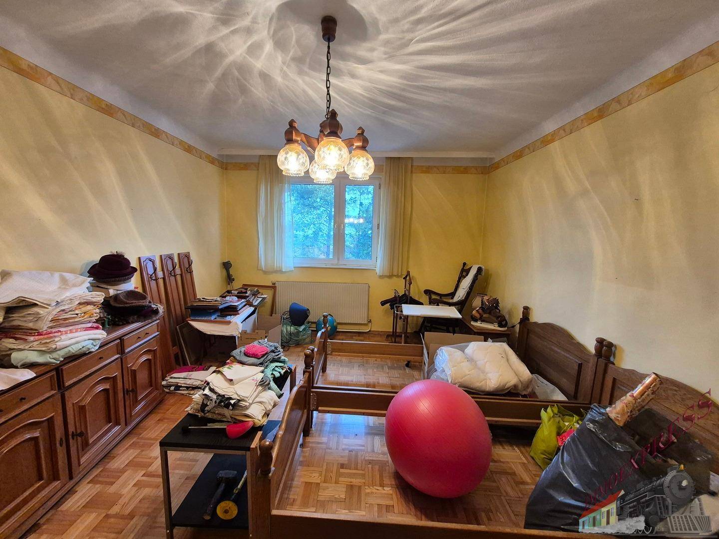 Schlafzimmer mit gelben Wänden, Parkettboden und mehreren Betten.