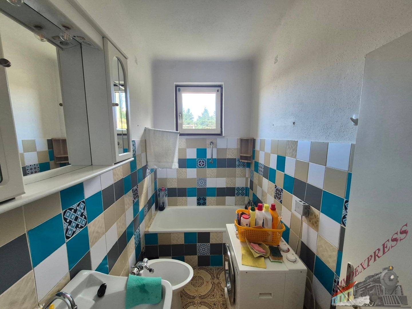 Badezimmer mit farbenfrohen Fliesen, Badewanne, Bidet und Fenster.