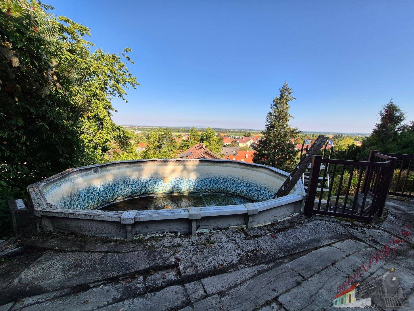 Alter, oberirdischer Pool mit Blick auf die weite Landschaft und die darunter liegende Stadt.