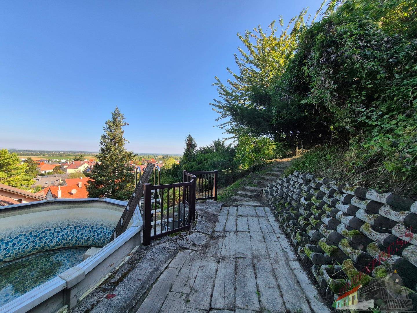 Steiler Weg im Gartenbereich mit Blick auf die umliegende Stadt und einen Pool.