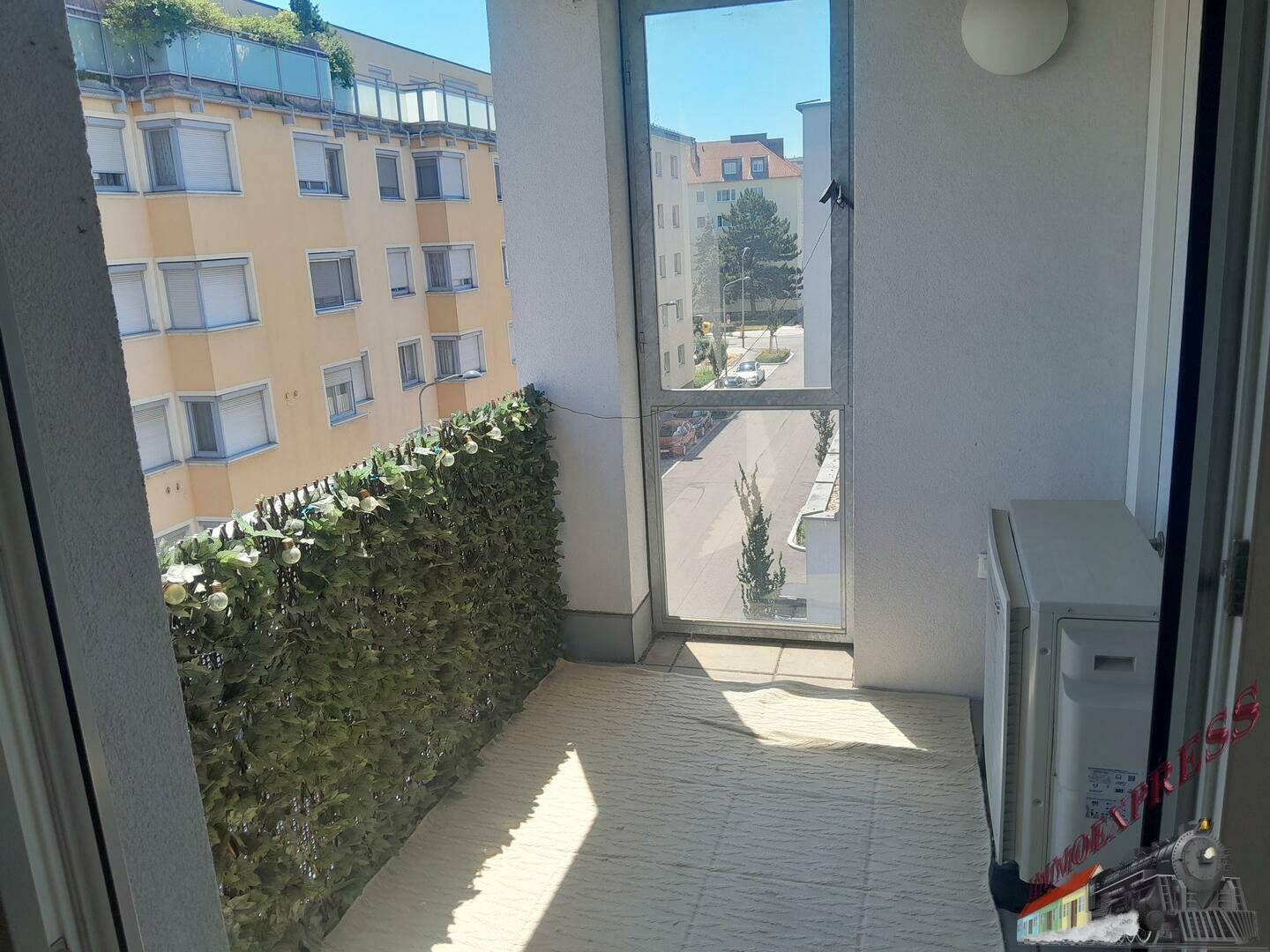 Kleiner Balkon mit Blick auf die Straße und umliegende Gebäude.