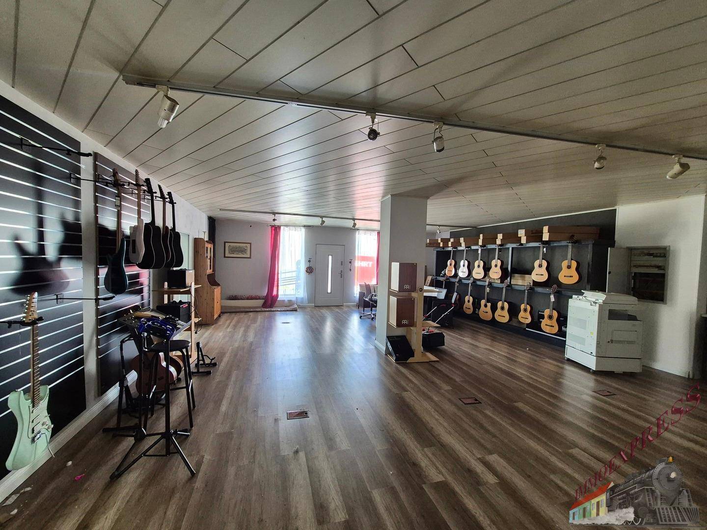 Weitläufiger Verkaufsraum mit Gitarrenausstellung, Holzboden und moderner Beleuchtung.