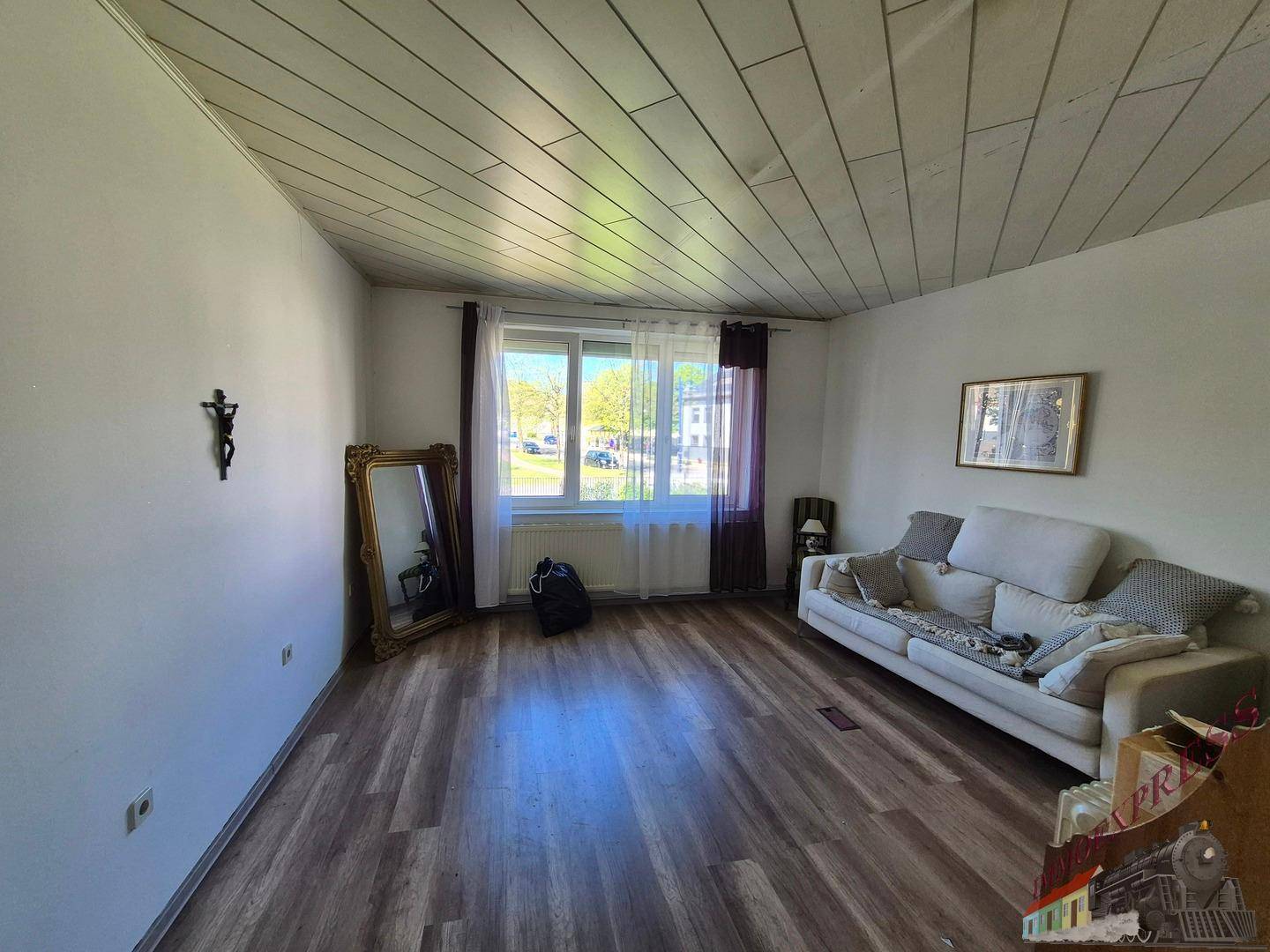 Helles Wohnzimmer mit Holzboden, Sofa und einem großen Spiegel an der Wand.