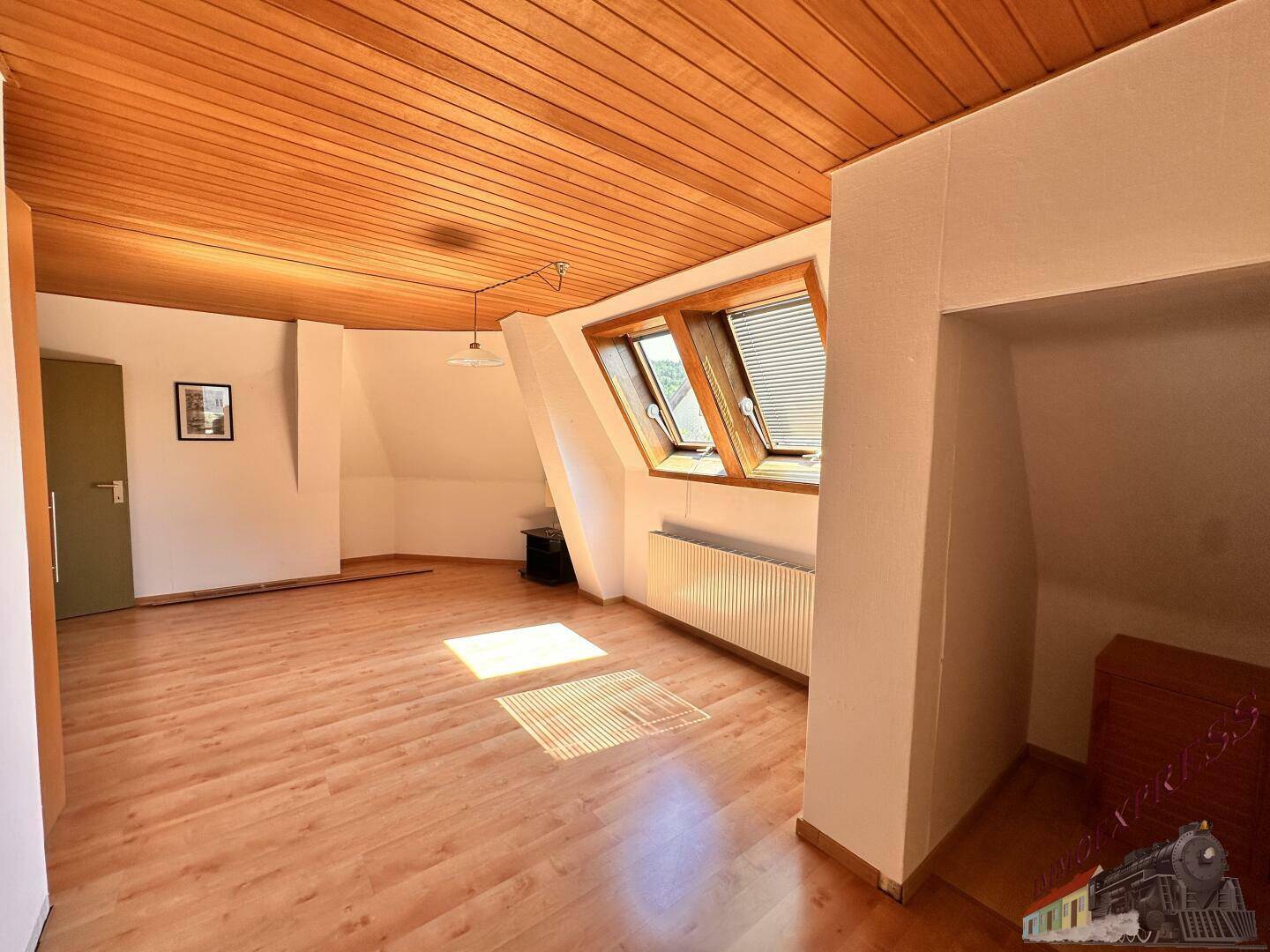 Helles Dachzimmer mit Holzdecke, Laminatboden und zwei Dachfenstern für viel Licht.