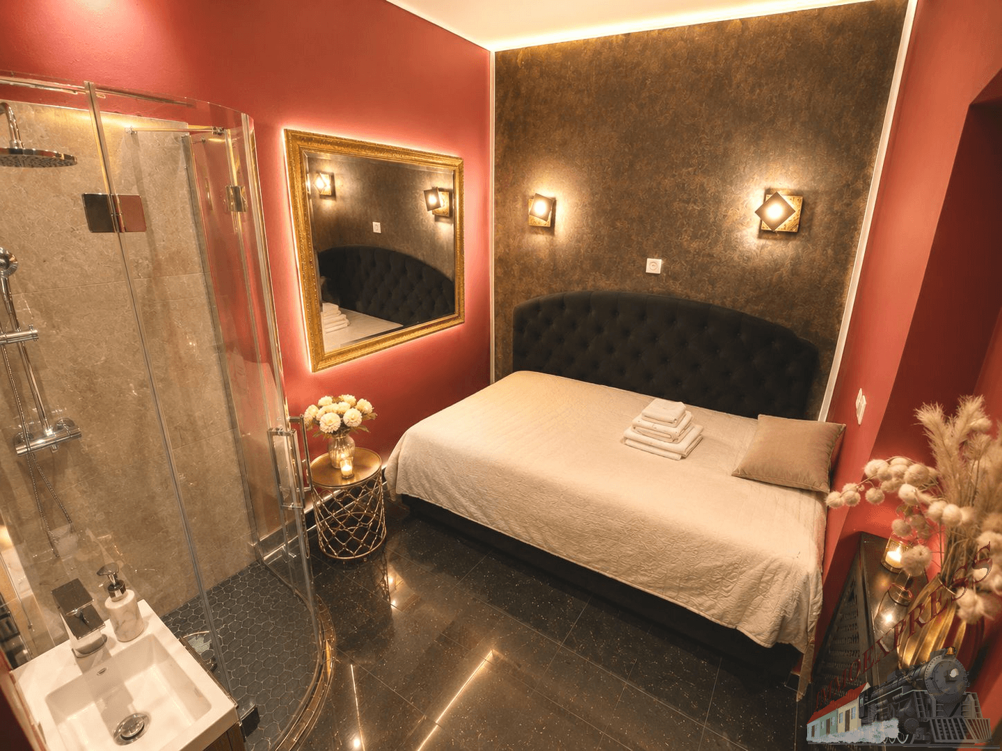 Gemütliches Schlafzimmer mit dunklem Polsterbett, offener Dusche und roter Wandgestaltung.