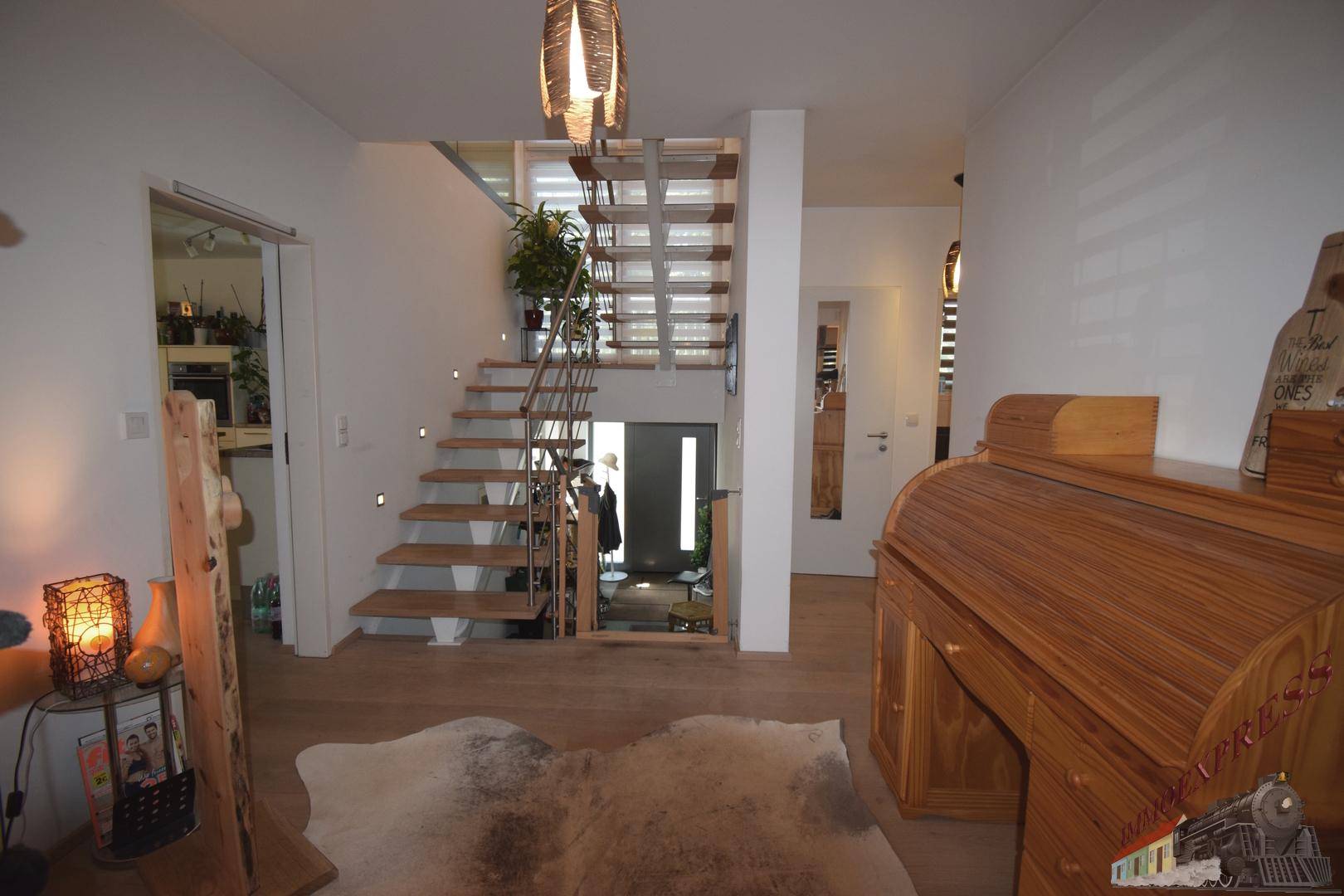 Heller Eingangsbereich mit Holztreppe, modernen Geländern und Holzboden.