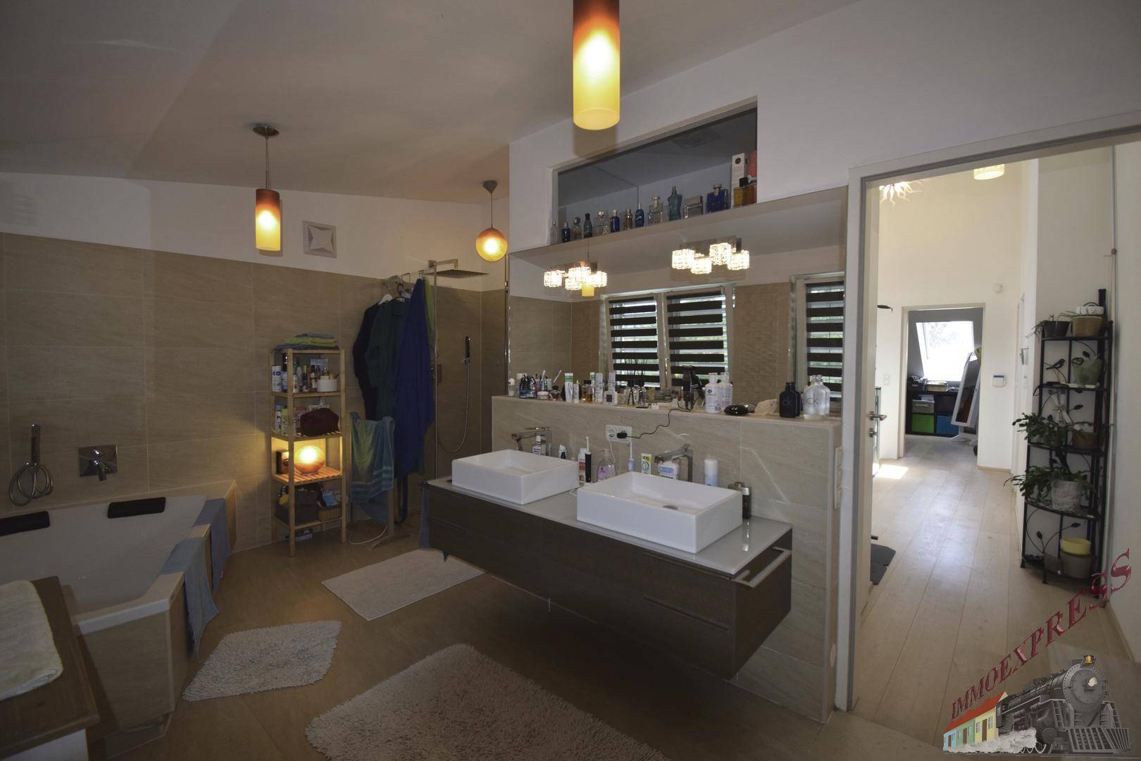 Geräumiges Badezimmer mit Doppelwaschbecken, Badewanne und modernen Fliesen in Erdtönen.