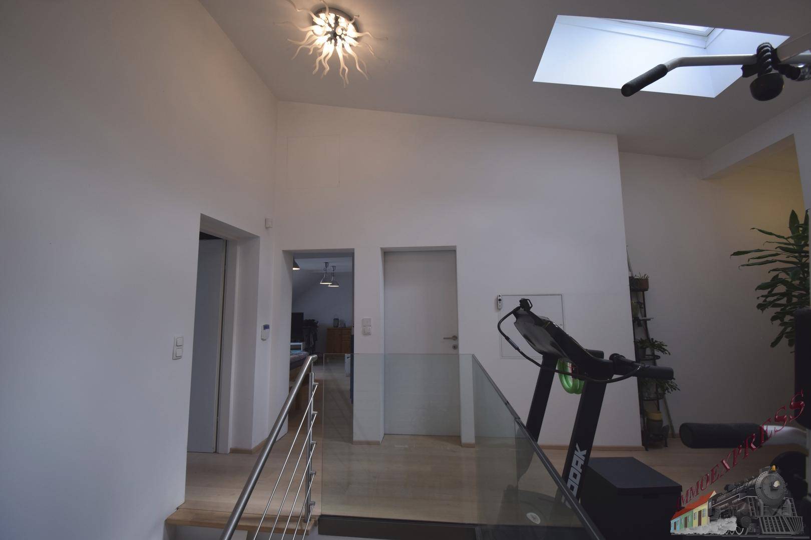 Heller Flur im Obergeschoss mit Fitnessbereich, Dachfenster und Zugang zu weiteren Räumen.